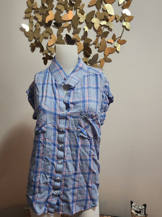 Blue plaid shirt on a white surface with decorative wall in the background