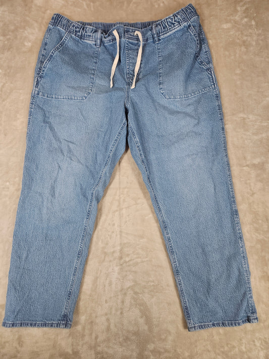 Pair of blue jeans laid flat on a beige surface